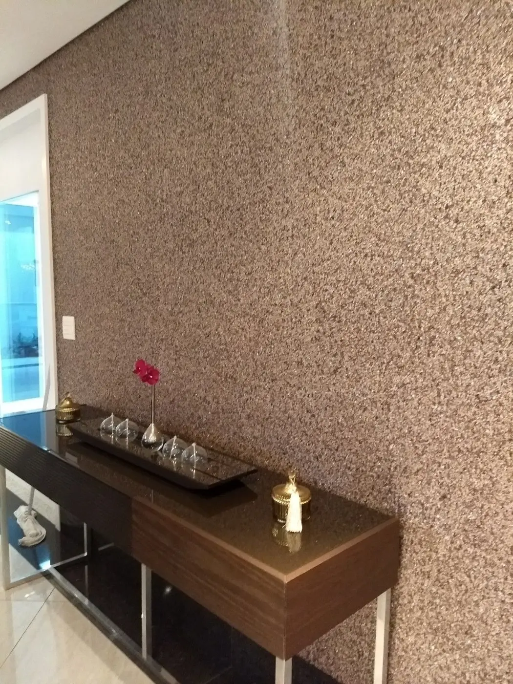 Sala com parede revestida em pedra natural tom bronze, aplicação da GS Revestimentos